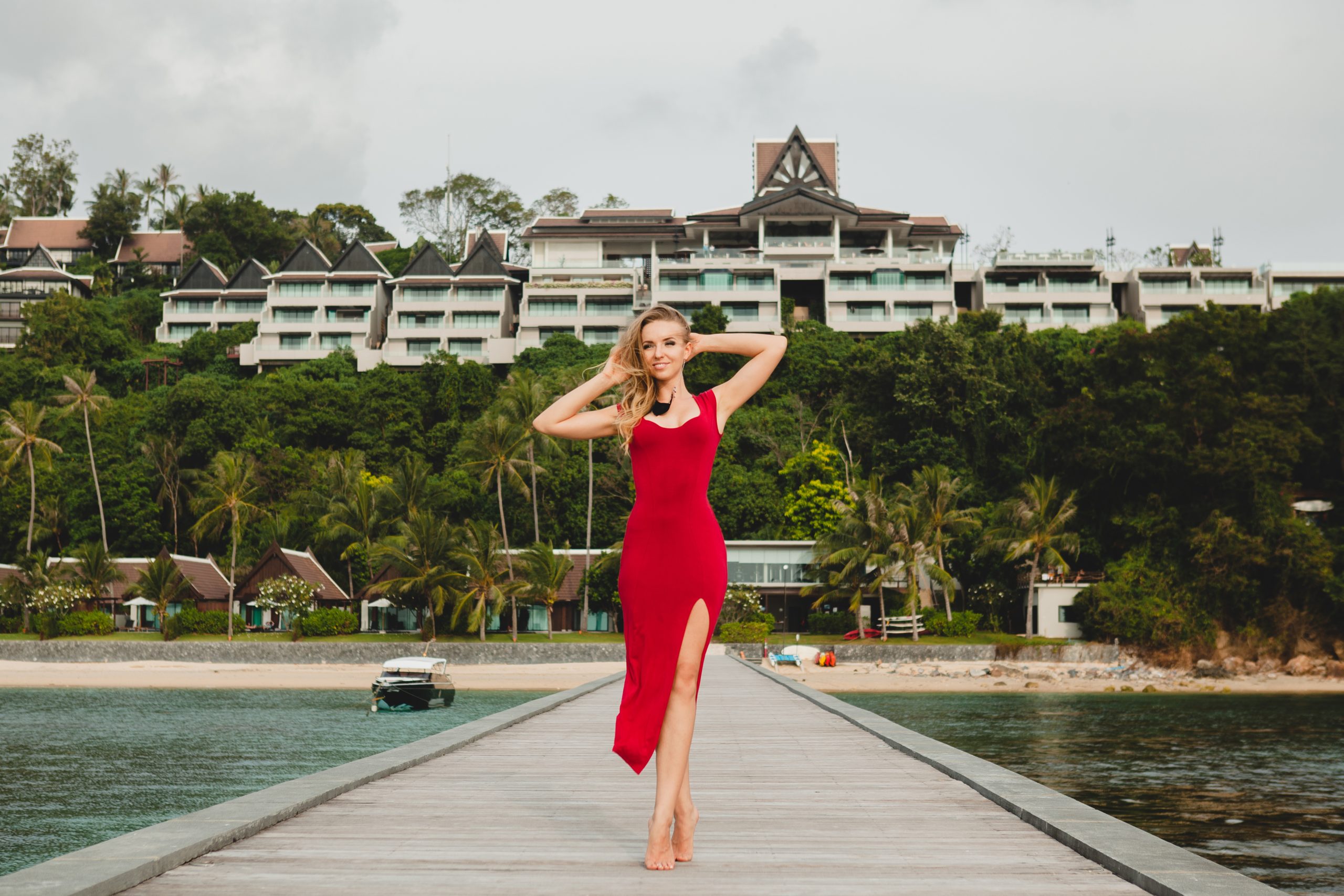 Kelsey Holmer leak young beautiful attractive woman standing alone on pier in luxury resort hotel, summer vacation, red long dress, blond hair, sexy apparel, tropical beach, seductive, sensual, smiling